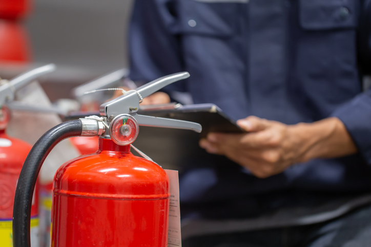 person checking fire extinguishers tank for safety training and fire prevention